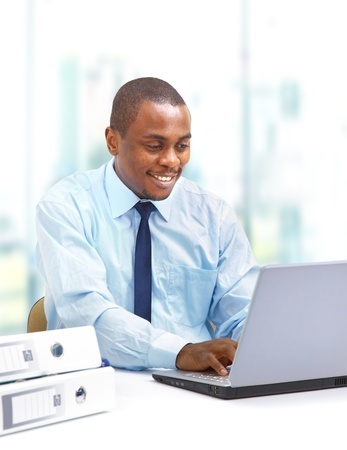 African man on laptop trading stocks